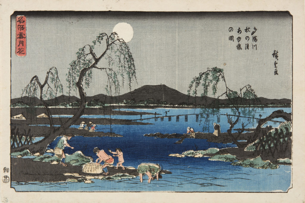 Japanese print of a river scene, fishermen dressed in loin cloths and traditional clothes, stand on the banks with baskets, others wade and bend over in the water, In the distance is a bridge, mountains and a full moon.