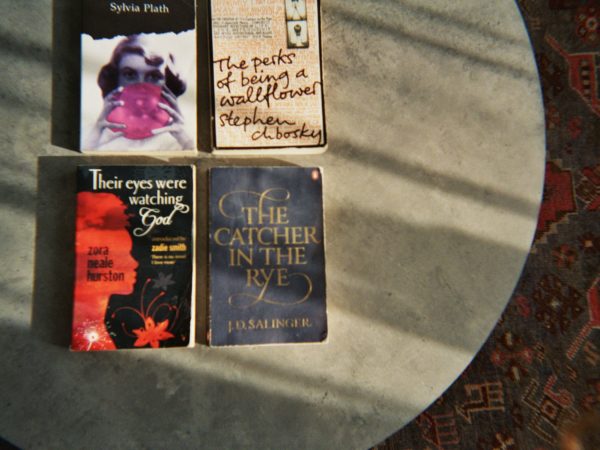 Abbi's photograph (for the 21st Century Kids) of four books, [The Catcher in the Rye by J.D Salinger, The Perks of Being a Wallflower by Stephen Chbosky, Their eyes were watching god by Zora Neale Hurston and a book by Sylvia Plath, The title of the book isn't shown]