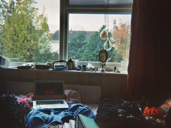 Beatriz's photograph (for the 21st Century Kids) of her bed with laptop on it. Above is her windowsill where there is her mirror and makeup. Outside the window are trees.