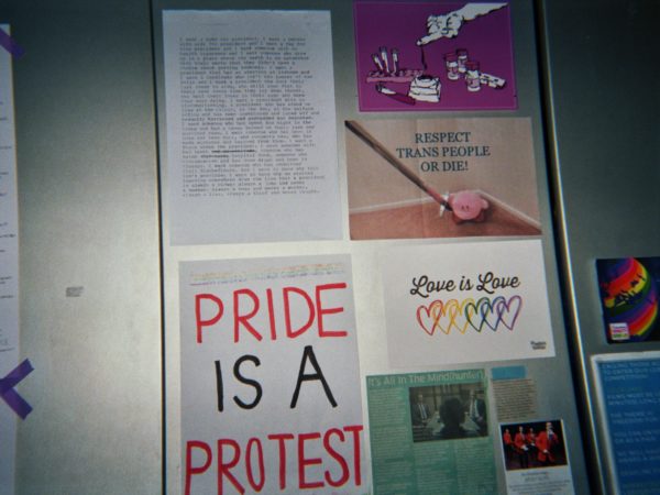 Elio's photograph (for the 21st Century Kids) of his wardrobe doors with activism posters some saying "PRIDE IS A PROTEST" and "love is love".