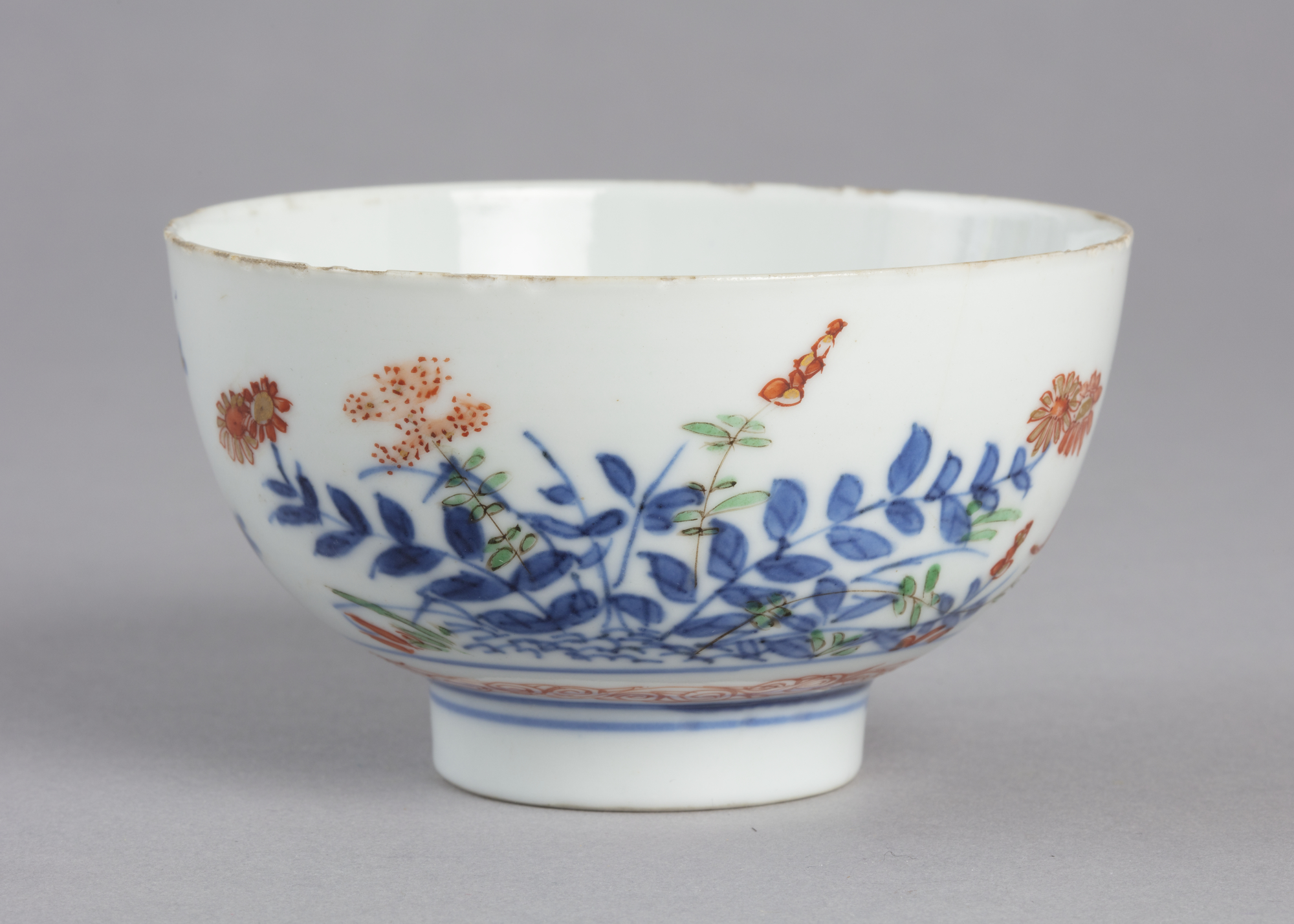 Bowl with design of flowers and grasses in blue, orange and green paint