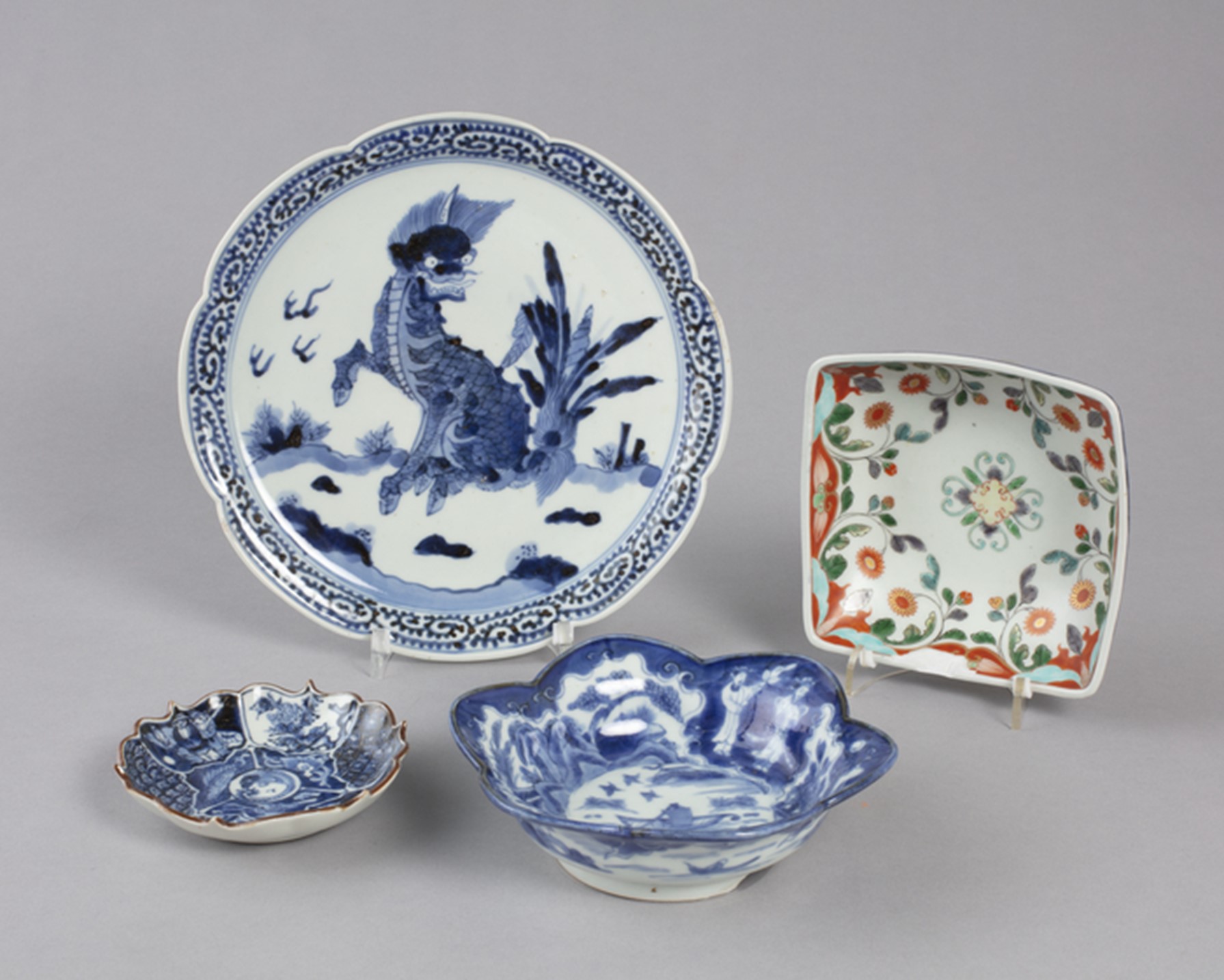 a group of four japanese porcelain plates and bowls, intricately decorated