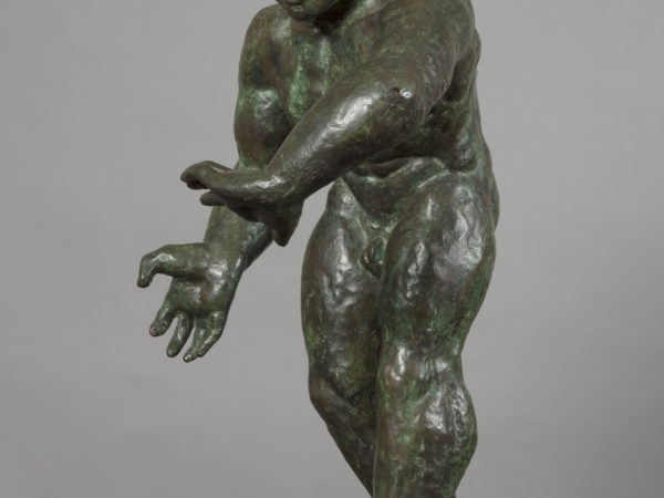 A bronze sculpture of a naked man shown as well-muscled wrestler facing left, with thick legs and arms, who leans inwards with hands poised as if to grapple an opponent.