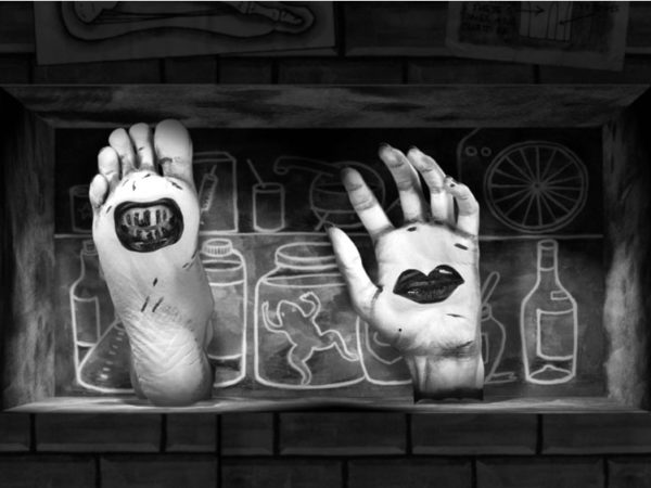 A black and white drawn image which shows a severed hand and foot in front of a line drawing of bottles and jars.
