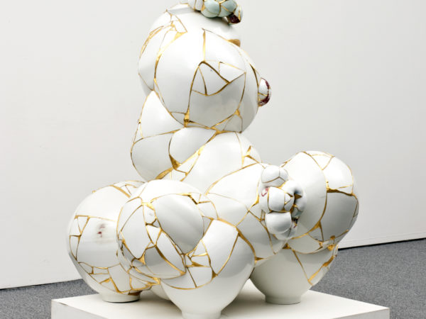 A sculpture made of a series of broken porcelain sherds fused together with gold leaf to create a series of irregular spherical shapes resembling bubbles joined together.