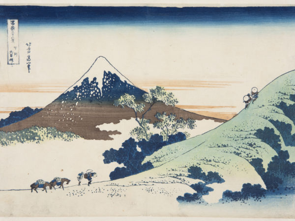 Japanese print of Inume Pass in Kai Province. Travellers with horses climb the hill in the foreground. Mount Fuji rises up in the background.