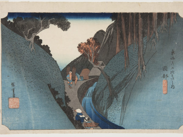 japanese print of a beautiful blue scene of a view through mountains, showing travelers walking up a very steep path and a waterfall next to the path