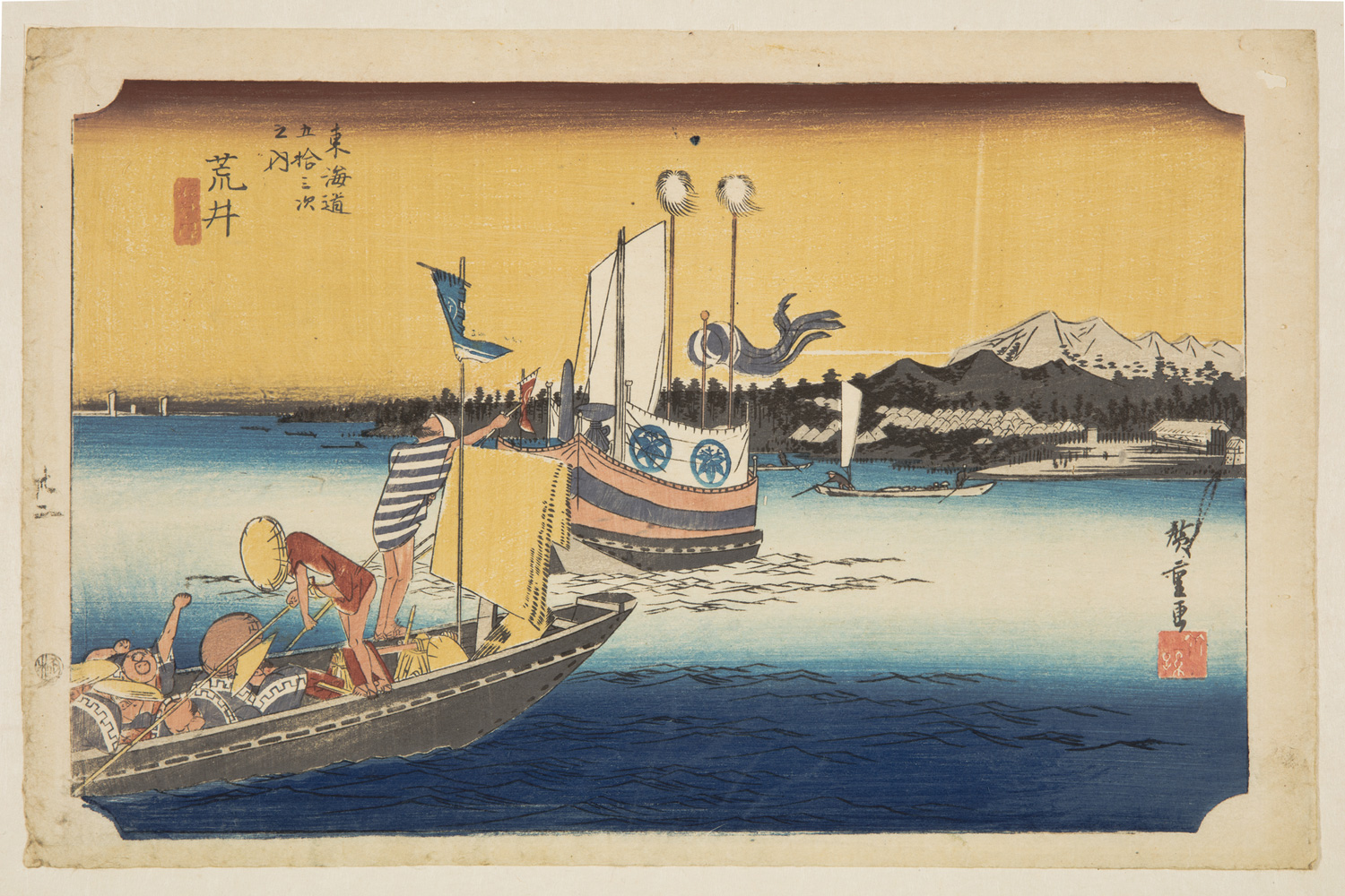 A Japanese print of boats on the water. The boat in the foreground is full of passengers, two men standing push the boat along with poles. The shoreline can be seen in the background, village, woods and mountains.