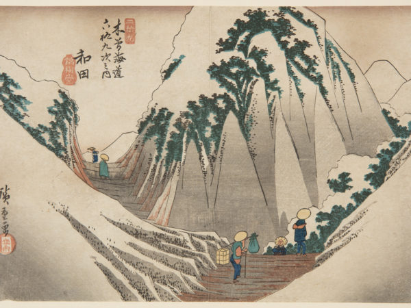 Japanese print of a road weaving through high mountains. Small figures walk along in traditional dress, the nearest carries a pole on his shoulder with bundles tied at each end.