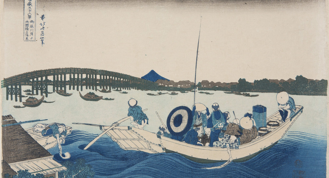 Japanese print of a river scene. In the foreground there are waves and a boat full of passengers, the boatman steers with a pole. Many boats are on the water and a bridge spans the river. The far bank has buildings and trees and Mount Fuji is in the distance.
