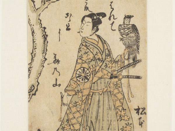 A Japanese print of an actor dressed in traditional robes by a tree. Two swords are visible and he holds a bird of prey on his left arm.