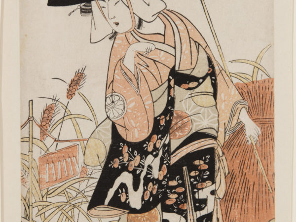 A Japanese print of an actor standing in a rural scene, looking down over the shoulder and wearing a large hat and long traditional robes.