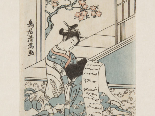 Japanese print of a woman dressed in traditional clothes, she sits by a window with blossom outside, and reads a long scroll of paper, a cat playfully grabs the paper from under the bench.