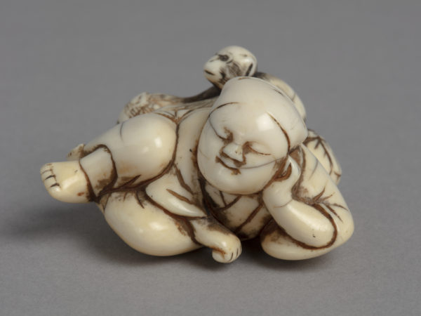 A Japanese ivory netsuke of a monkey stealing from a basket behind the back of a sleeping monkey trainer.