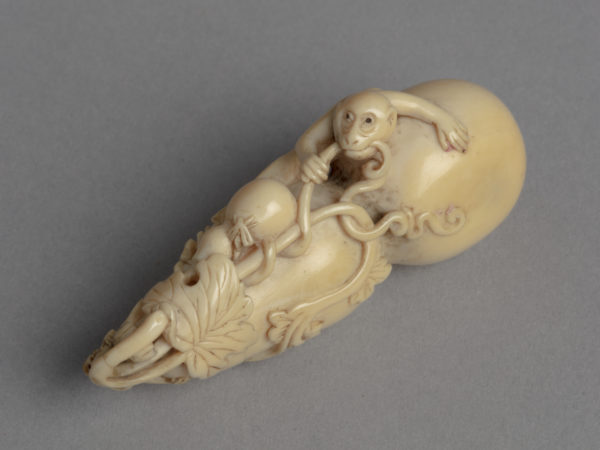 A Japanese ivory netsuke of a double gourd. The top opens and inside is a fine chain from which hang three monkeys.