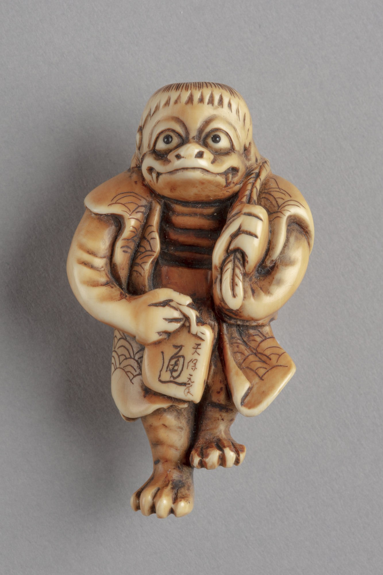 A Japanese ivory netsuke of a kappa, a goblin-like mythical creature. It carries a sake flask slung over its left shoulder.