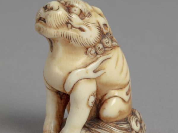 A Japanese ivory netsuke of a seated kirin, a mythical creature that is part dragon, deer, horse, and lion.