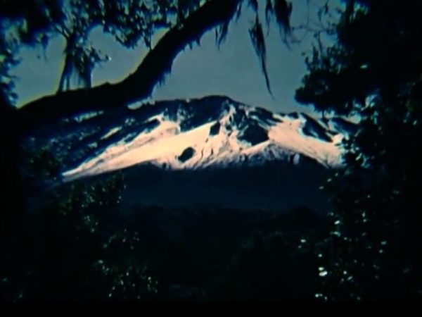Still from footage showing a snowy side view of Mount Kilimanjaro (taken by Ivan Haslam) recording an ascent of Mount Kilimanjaro by a group of South Asians, with African guides and porters, taken in the 1950s.