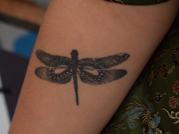 a detailed dragonfly tattoo on a forearm