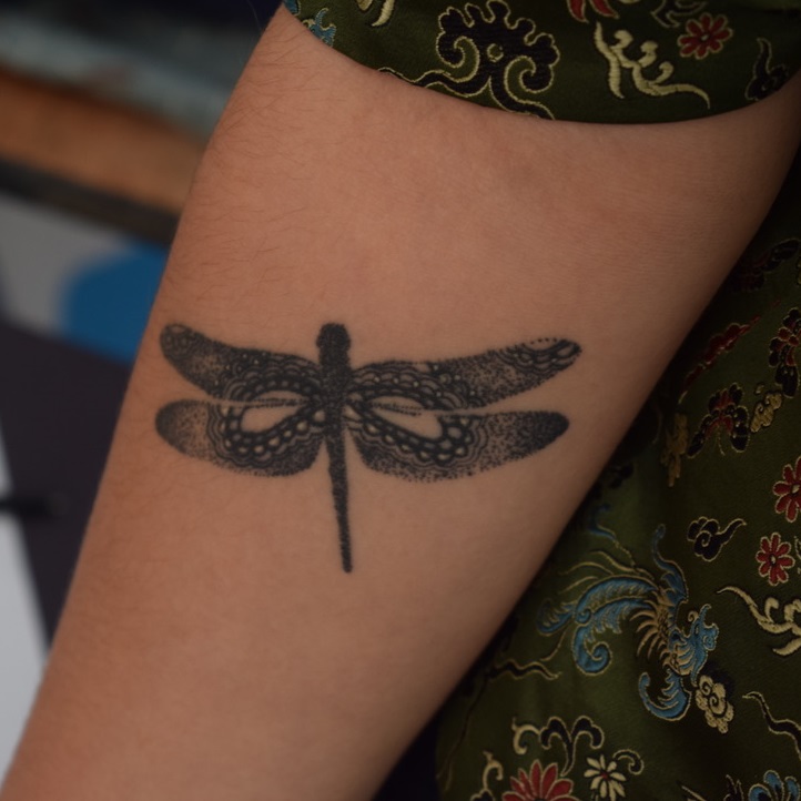 a detailed dragonfly tattoo on a forearm