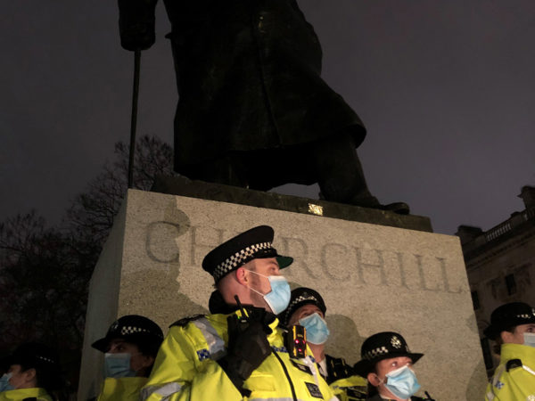 Statue of Winston Churchill, guarded by police in high vis jackets.