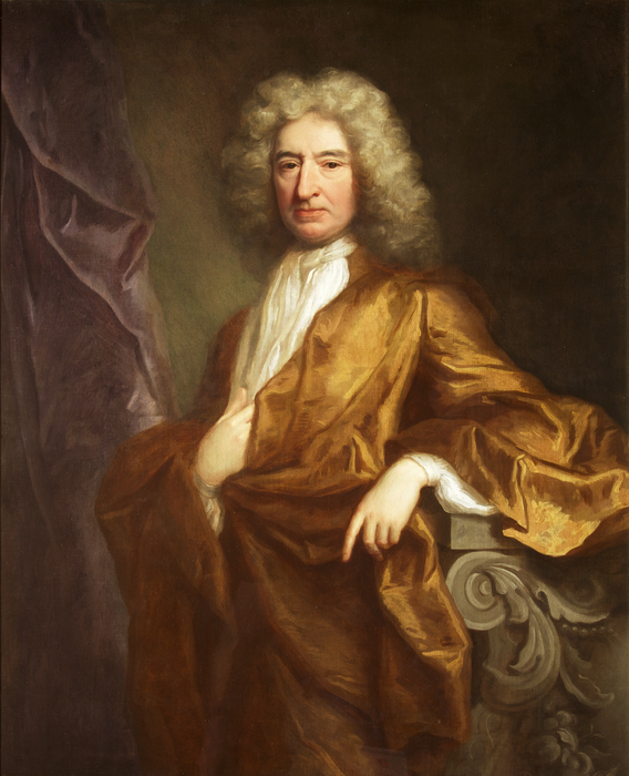Portrait of Edward Colston. Painting of a man, looking at the viewer. He wears a loose bronze coloured robe, over a white shirt and long white necktie. His hair/ wig is long and grey. His left lower arm rests on a wooden rest. His right hand rests on his body, above the stomach, tucked into the fabric slightly. There is a dark background and a purple drape to the left of the painting.